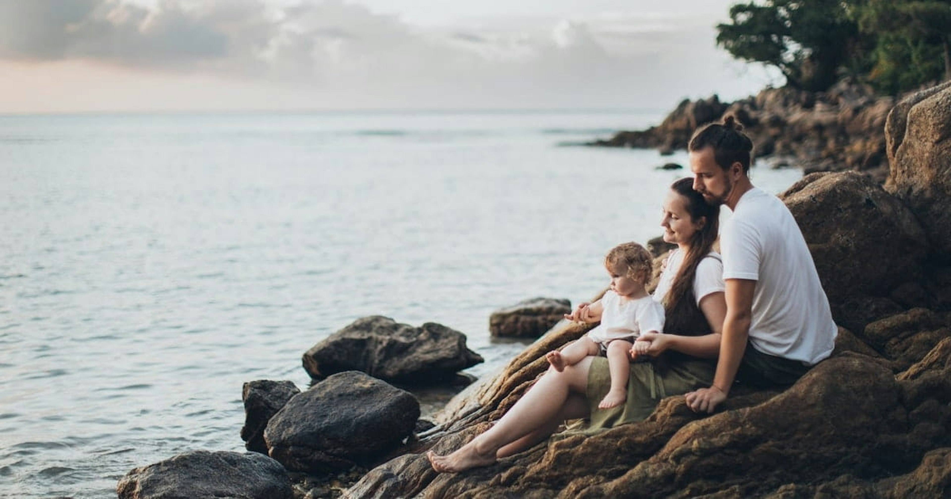 Family sitting on rock near seashore